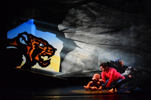 The shadow of a tiger at the mouth of a cave which hides a boy and a monkey