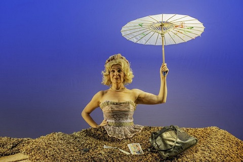 Production photo showing a woman holding an umbrella buried in the ground up to her waist