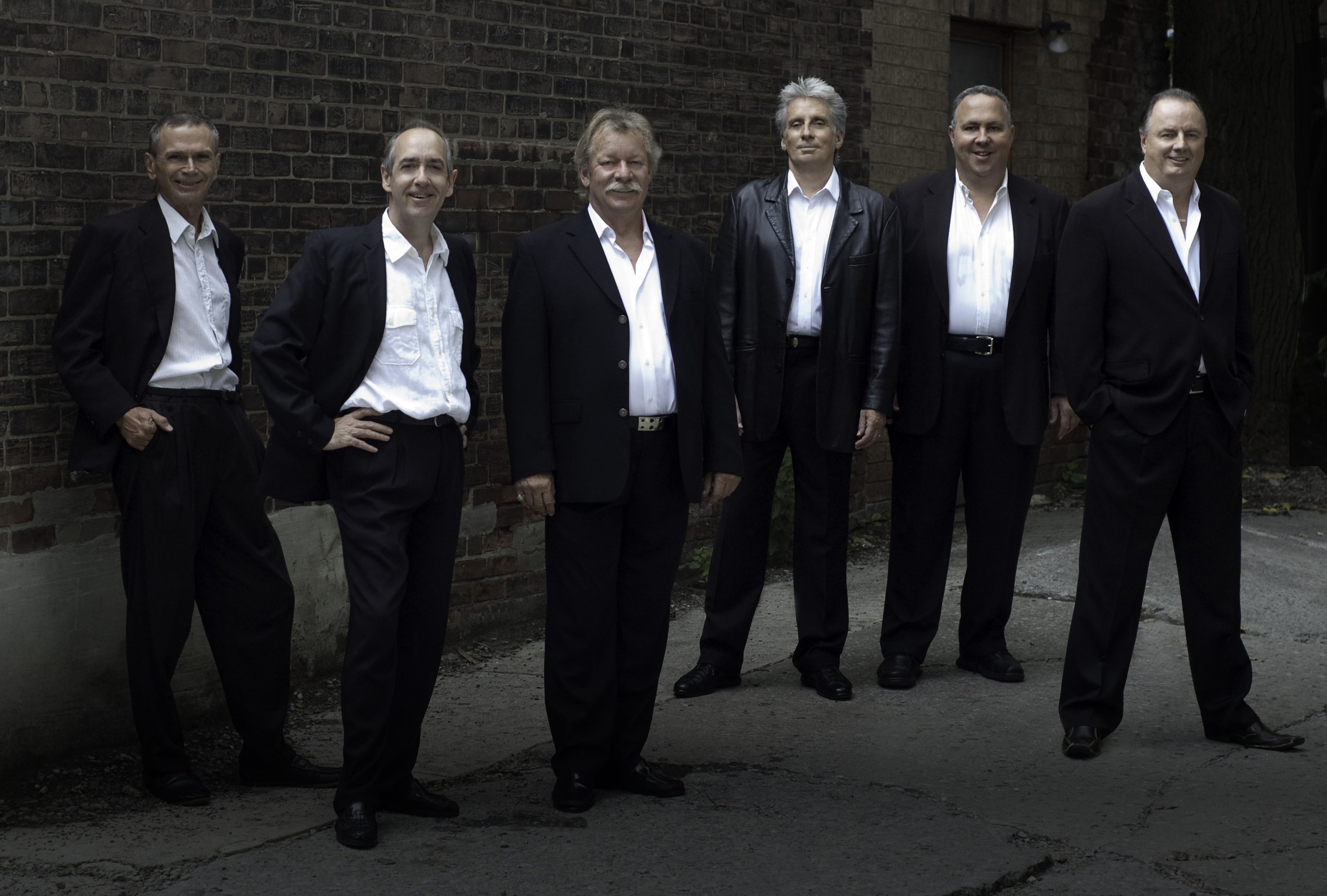 Four members of the band standing in suits. 
