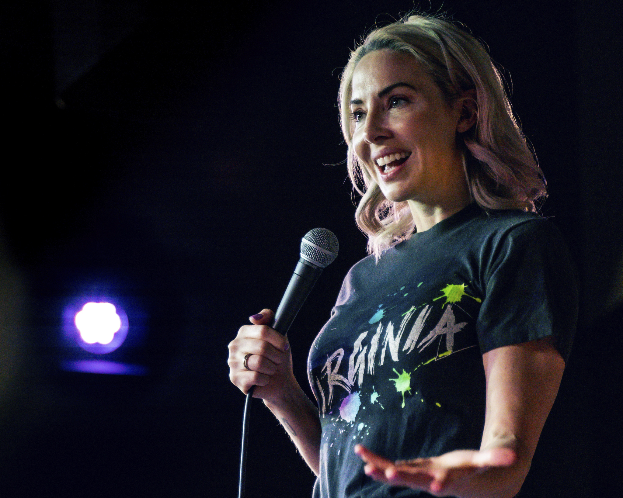 Whitney Cummings on stage with a micro phone in her right hand