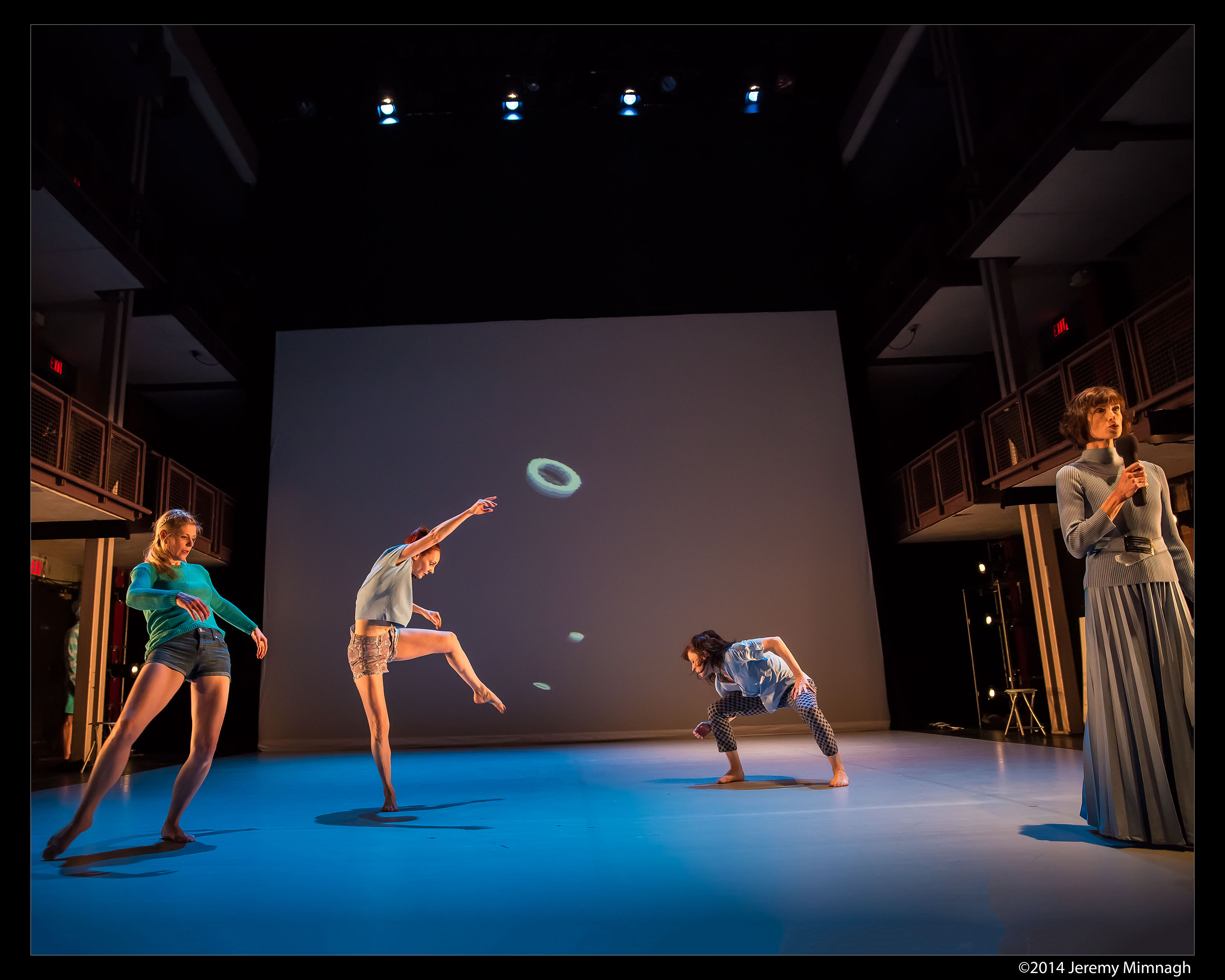 Dancers on stage in front of a drop down digital screen. 