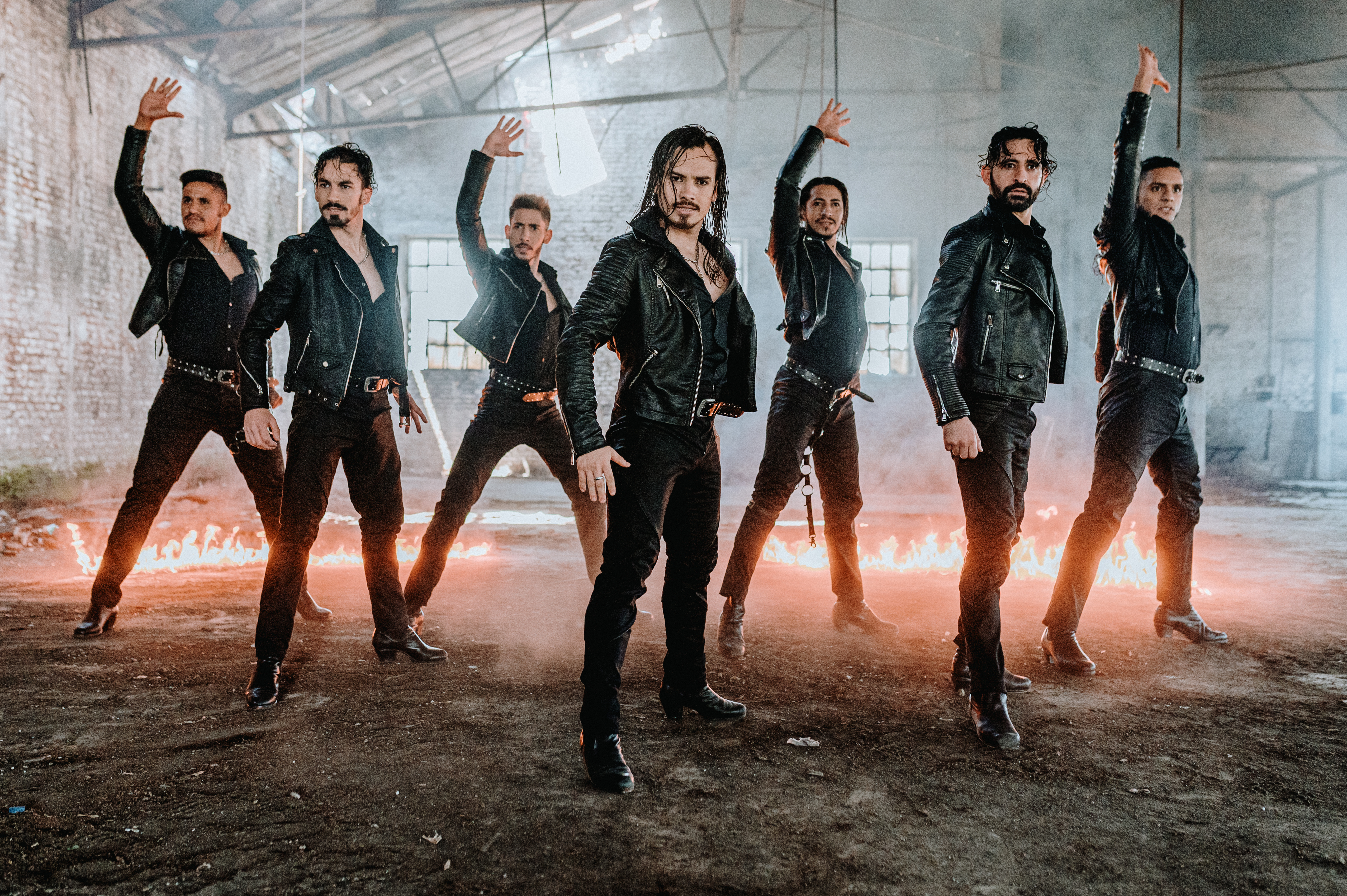 all male drummers with no drums, but fire on the ground behind them