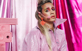 performer all in pink, with a body mic and sad expression on their face