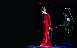 Molly Johnson in a long red dress, center stage