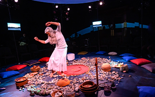 performer in white dancing in a round circle of stone on the ground