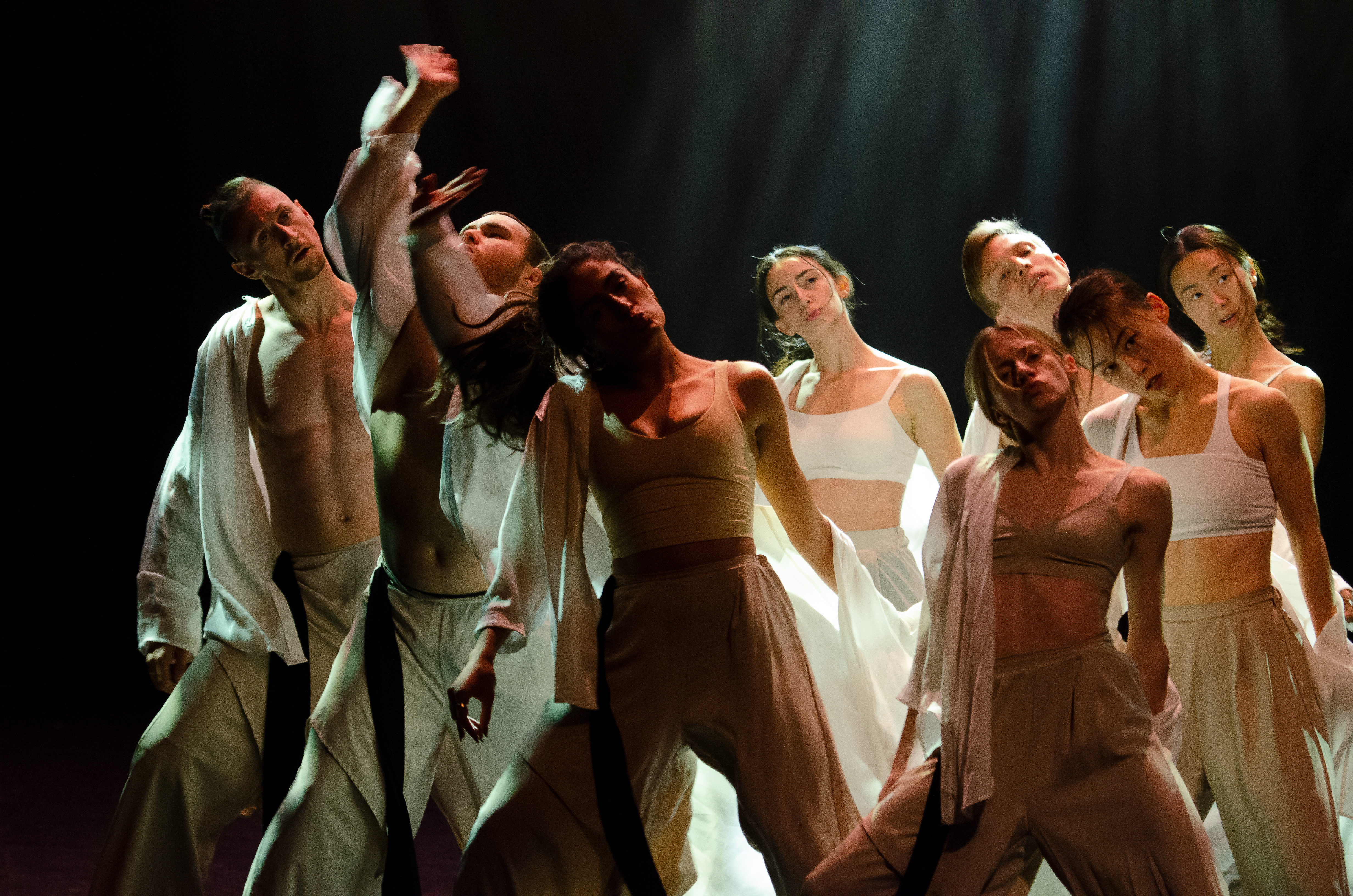 multiple dancers on stage, some with their arms in the air