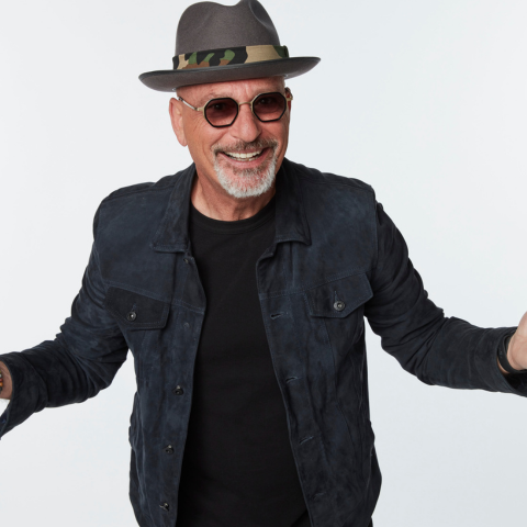 A man with hands outstretched wearing a hat and sunglasses