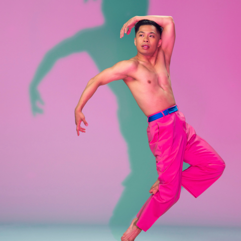 A shirtless dancer on stage in pink pants