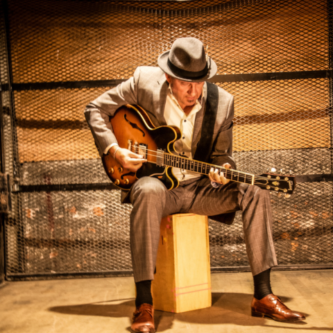 Man sitting on a box playing a guitar