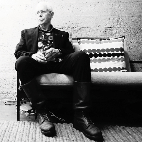 Bruce Cockburn sitting on a couch in a black and white image
