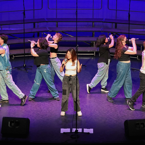 performers on stage singing and dancing wearing jeans