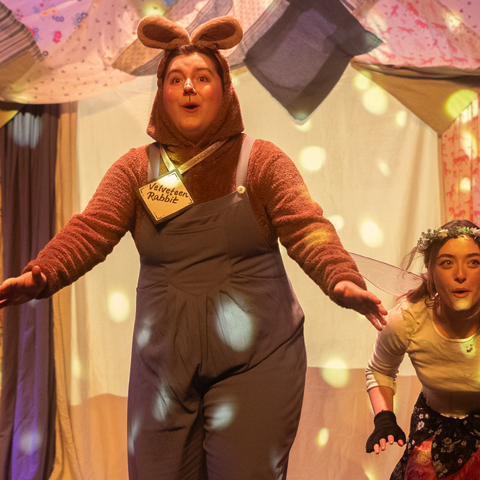 an actor dressed in animal ears with hands extended