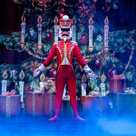 A nutcracker dressed in red with arms extended