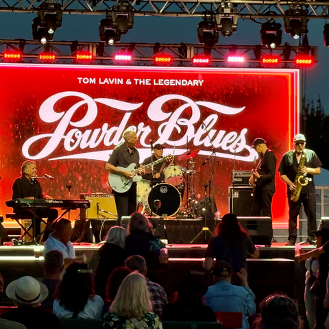 performers with Powder Blues sign in the back ground in red