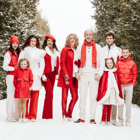 Natalie MacMaster, Donnell Leahy and family dressed in white and red poising for the camera outside with trees in the background 
