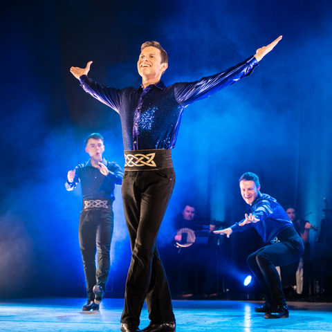 dancer with his arms extended all washed in blue light
