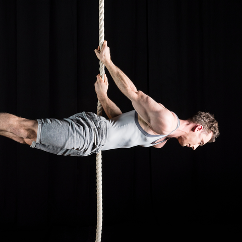 a performer hanging on a right completely horizontal with their body