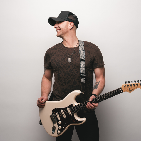 Tim Hicks holding a guitar looking off to the left