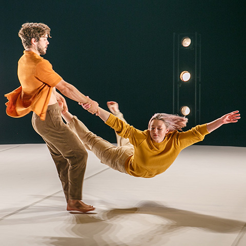two dancers with one swinging the other around by her hand and foot (think figure skating)