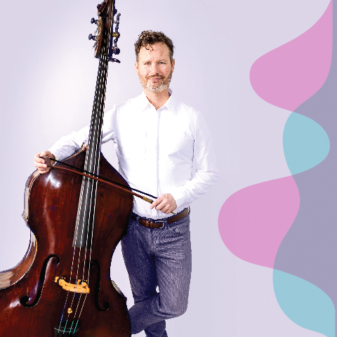 Bass player in a white shirt, standing beside his bass