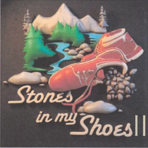 Artwork featuring a red shoe spilling stones beside a river and mountains, with the title ‘Stones in My Shoes II.’