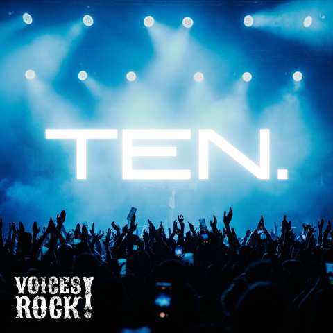 Concert crowd with raised hands in front of a stage lit blue, with the word ‘TEN.’ displayed in large white letters.