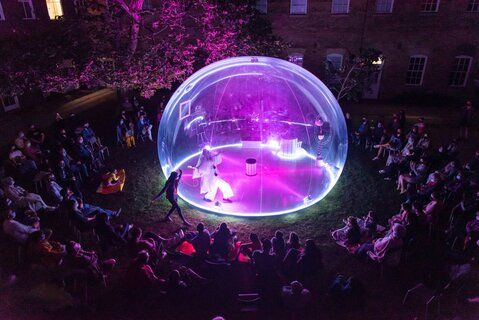 A mime performing inside an inflatable bubble with purple lights