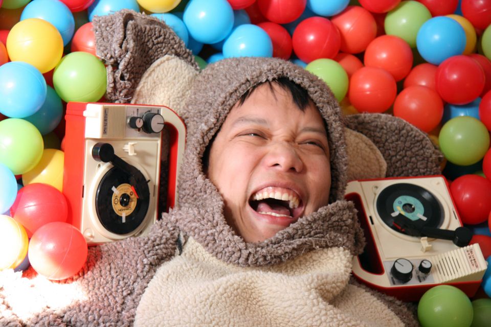 Kid Koala a smiling man in a koala costume surrounded by colourful balls