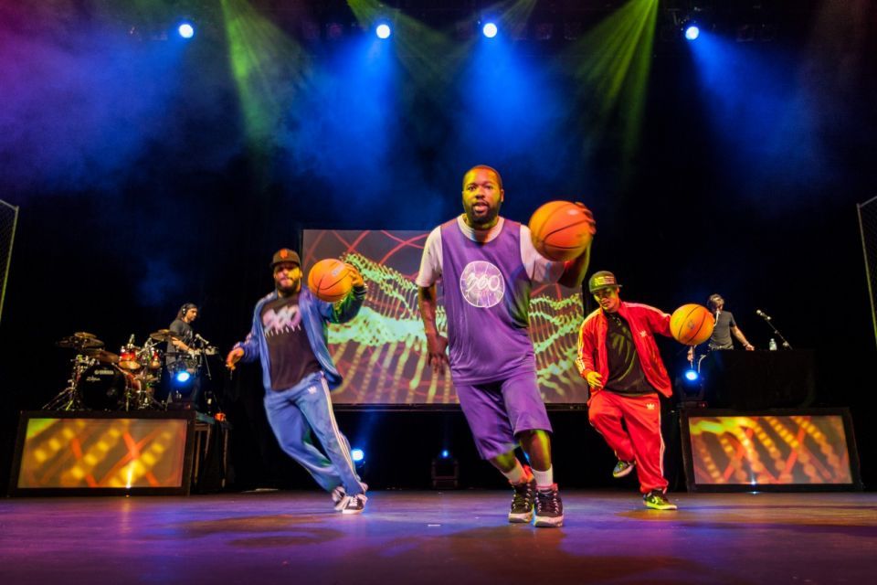 A group of athletic performers in various stunts using basketballs, bicycles and a giant hoop