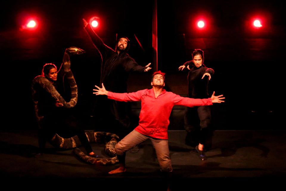 A man onstage with arms outstretched wearing a red shirt