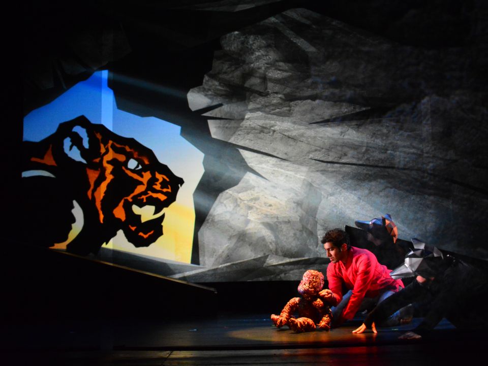 A menacing shadow of a tiger at the mouth of a cave with a young boy and monkey inside