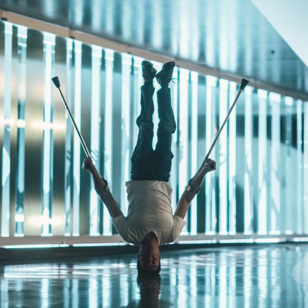 Dancer with crutches balancing on his head
