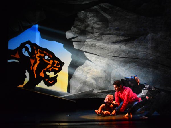 A menacing shadow of a tiger at the mouth of a cave with a young boy and monkey inside
