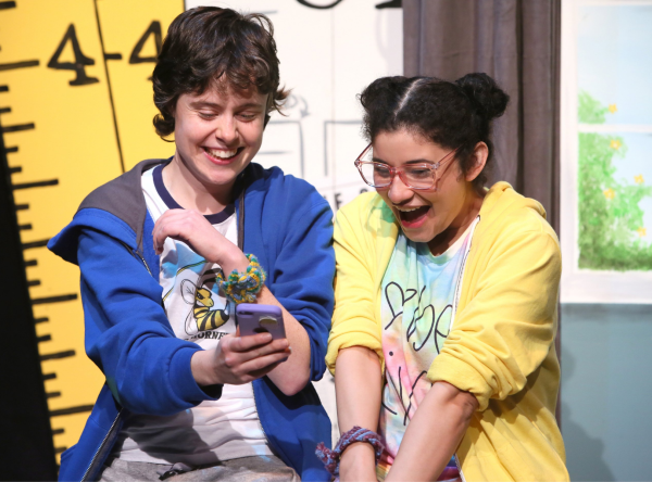 Like it or Not performed Green Thumb Theatre Two young female actors looking at a cell phone and laughing.