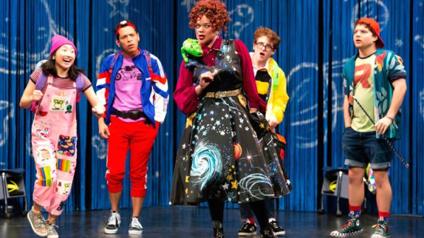 Group of performers wearing bright and colourful clothing standing on a stage. Photo of performers wearing bright and colourful clothing standing on a stage.