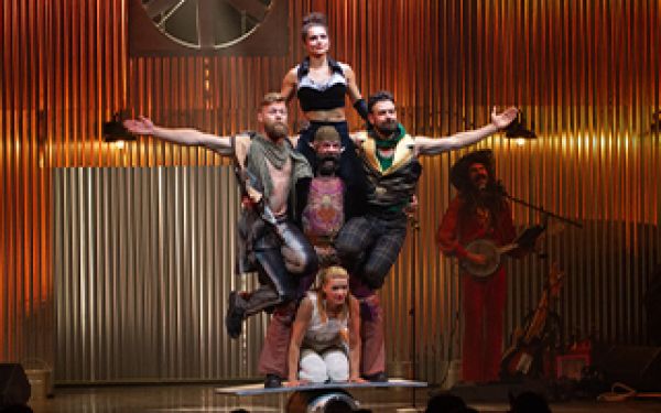 5 cirque performers balanced on a rounded barrel