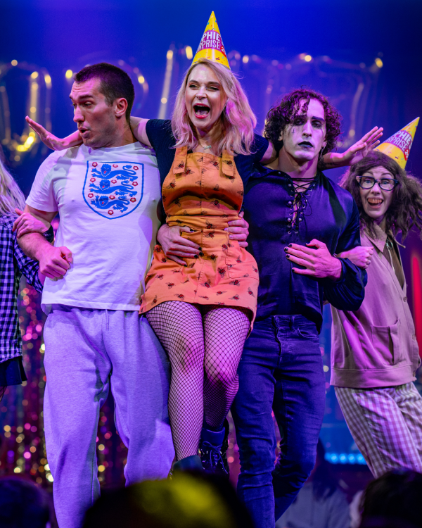 Performers on stage with birthday hats