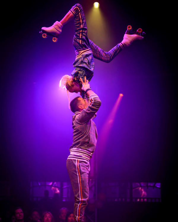 Performers hanging from a rope with a purple background