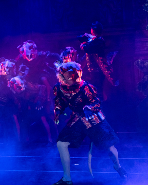 Dancers in dark colours on a stage washed in blue