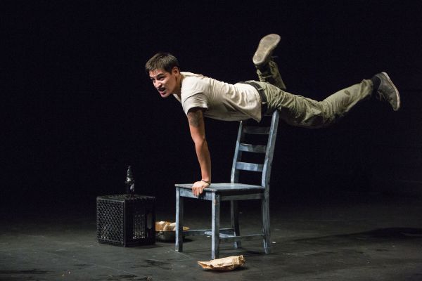 Man holding himself up off the back of a chair.