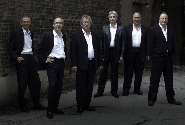 Four members of the band standing in suits. 