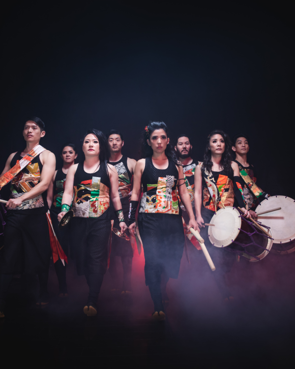 performers posing for the camera, some holding drums