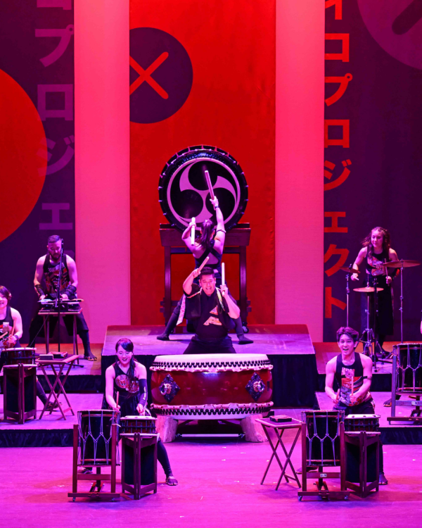 performers on stage drumming with purple and pink lights