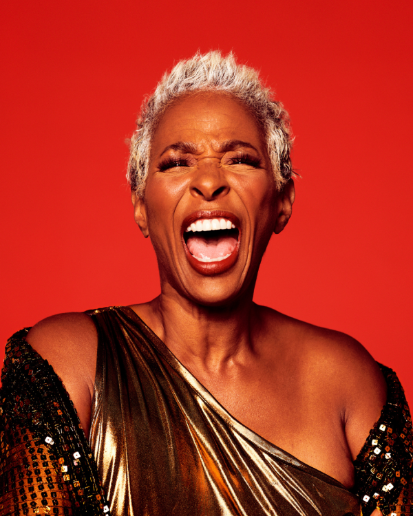 Shakura S'Aida headshot in front of an orange background looking like she is signing