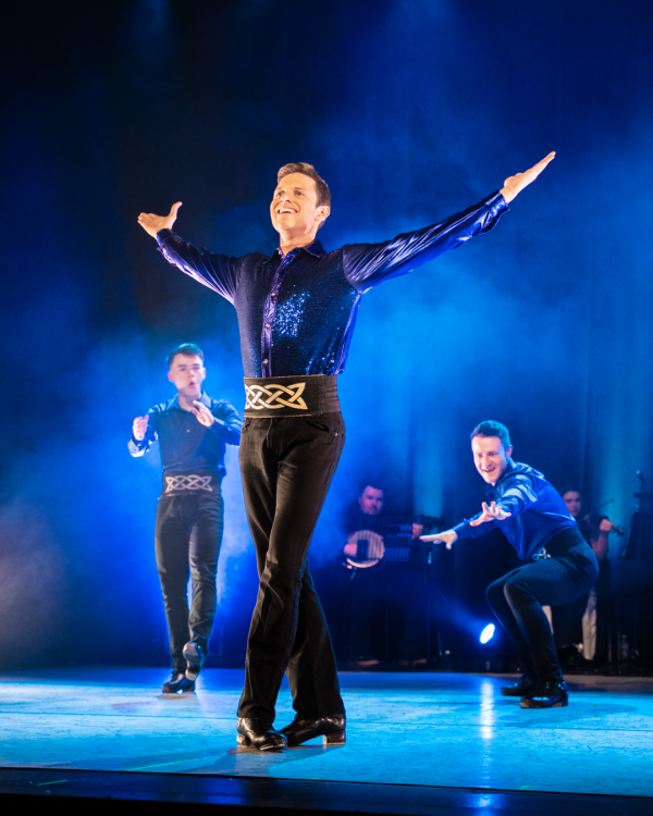 dancer with his arms extended all washed in blue light
