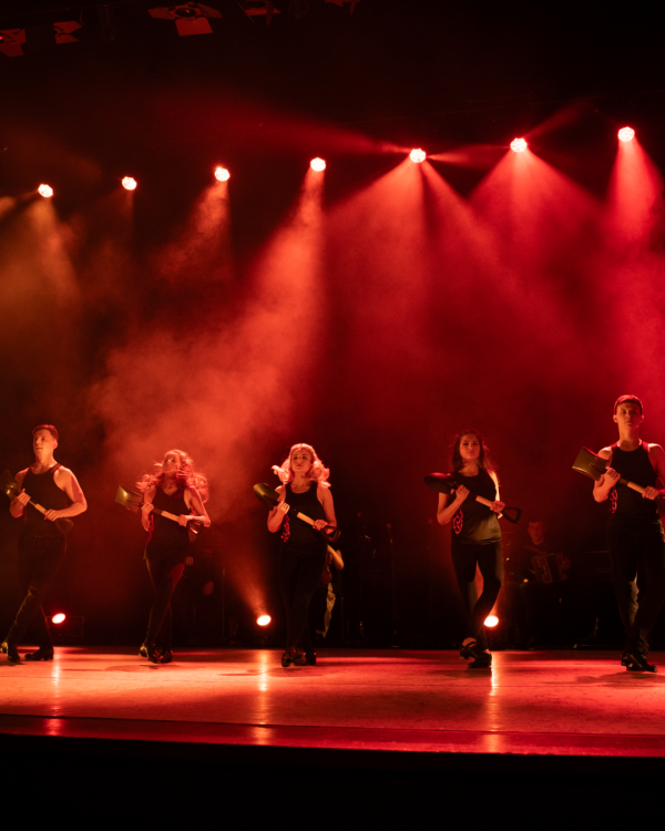 Dancers on stage with red lights shining down on them
