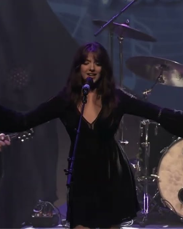 a female singing with arms extended