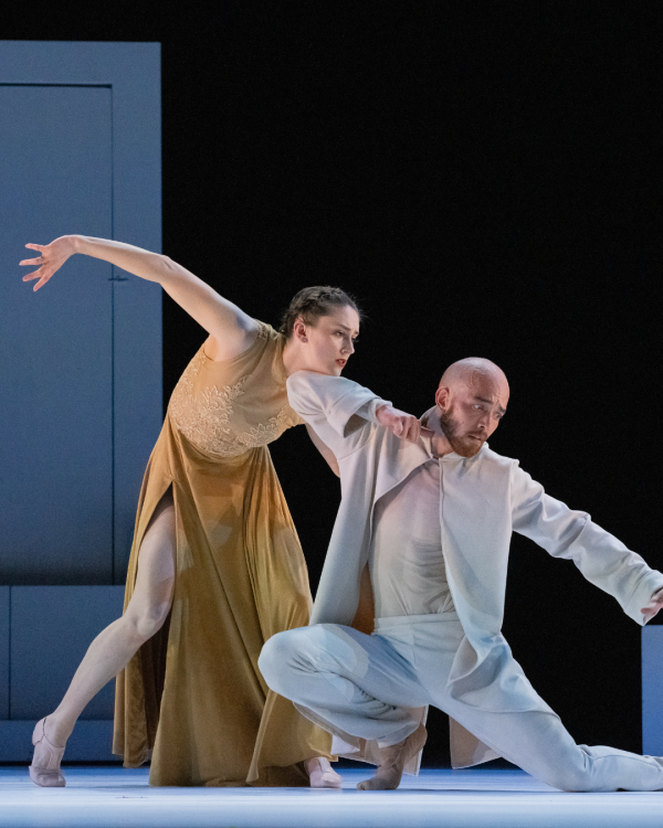 Dancers one in white and one in gold holding onto each other