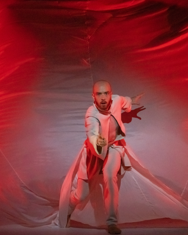 A dancer reaching out to the camera with red tint to the image