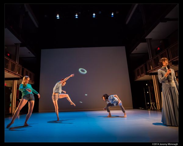 Dancers on stage in front of a drop down digital screen.